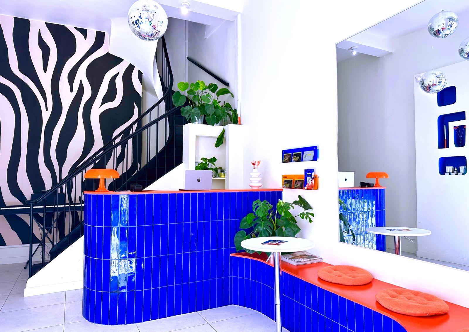 L'accueil du centre Haïko à Marseille : comptoir en carrelage bleu, banquette orange, mur zébré et escalier noir